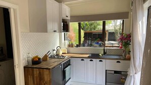 Una cocina compacta con armarios blancos, una encimera de madera y baldosas de suelo estampadas.
