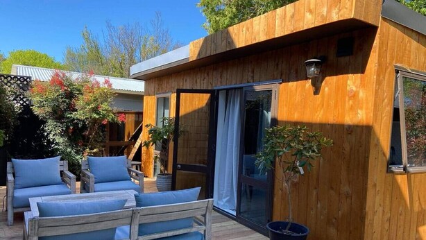 Una cabaña de madera con terraza, un sofá y una planta en maceta.