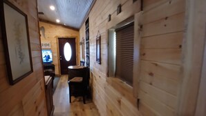 A wooden interior hallway with a dining area, a television, and a framed picture on the wall. - Cozy tiny cabin, close to local activities. Pet friendly. Suited 2 adults. (Owenton)