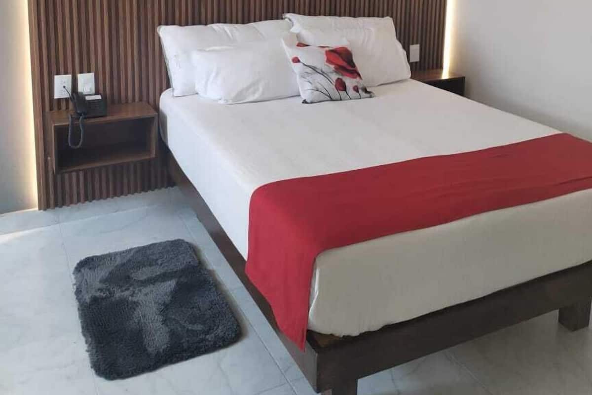 A modern hotel room with a large bed, a bedside table, and a headboard with vertical lines.