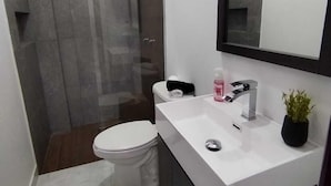 Une salle de bain moderne avec un lavabo blanc, un miroir et une douche.