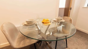 Mesa de jantar com tampo de vidro, cadeiras, uma tigela, uma banana e um copo.