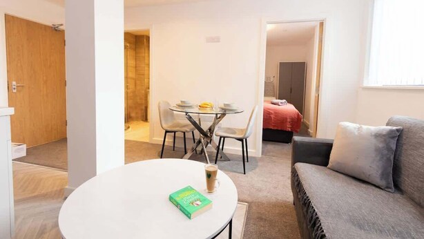 Uma sala de estar moderna com uma mesa redonda, um sofá e uma área de jantar com cadeiras.