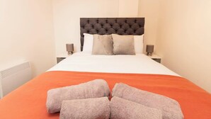 Quarto de hotel com cama, duas mesas de cabeceira e um radiador.