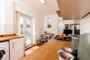 Cocina compacta con comedor, lavadora y vistas a través del ventanal.
