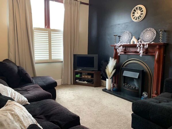A living room with a fireplace, a television, and a sofa set.