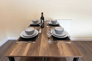 A dining table set with plates, bowls, wine glasses, and cutlery.