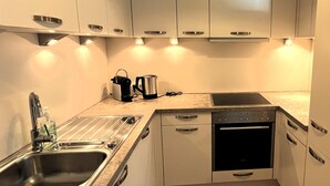 Een kleine keuken met een spoelbak, fornuis en koffiezetapparaat.