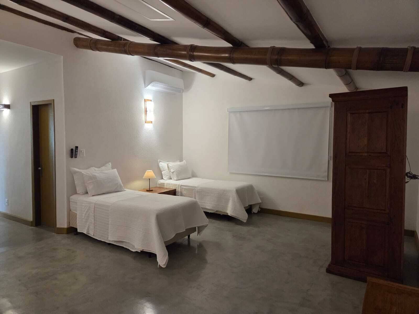 A room with two beds, a wooden door, and a window with blinds.