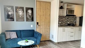A modern living room with a blue sofa, a small round table with a plant, and three framed artworks on the wall. - Varun Luxury  (Bogotá)