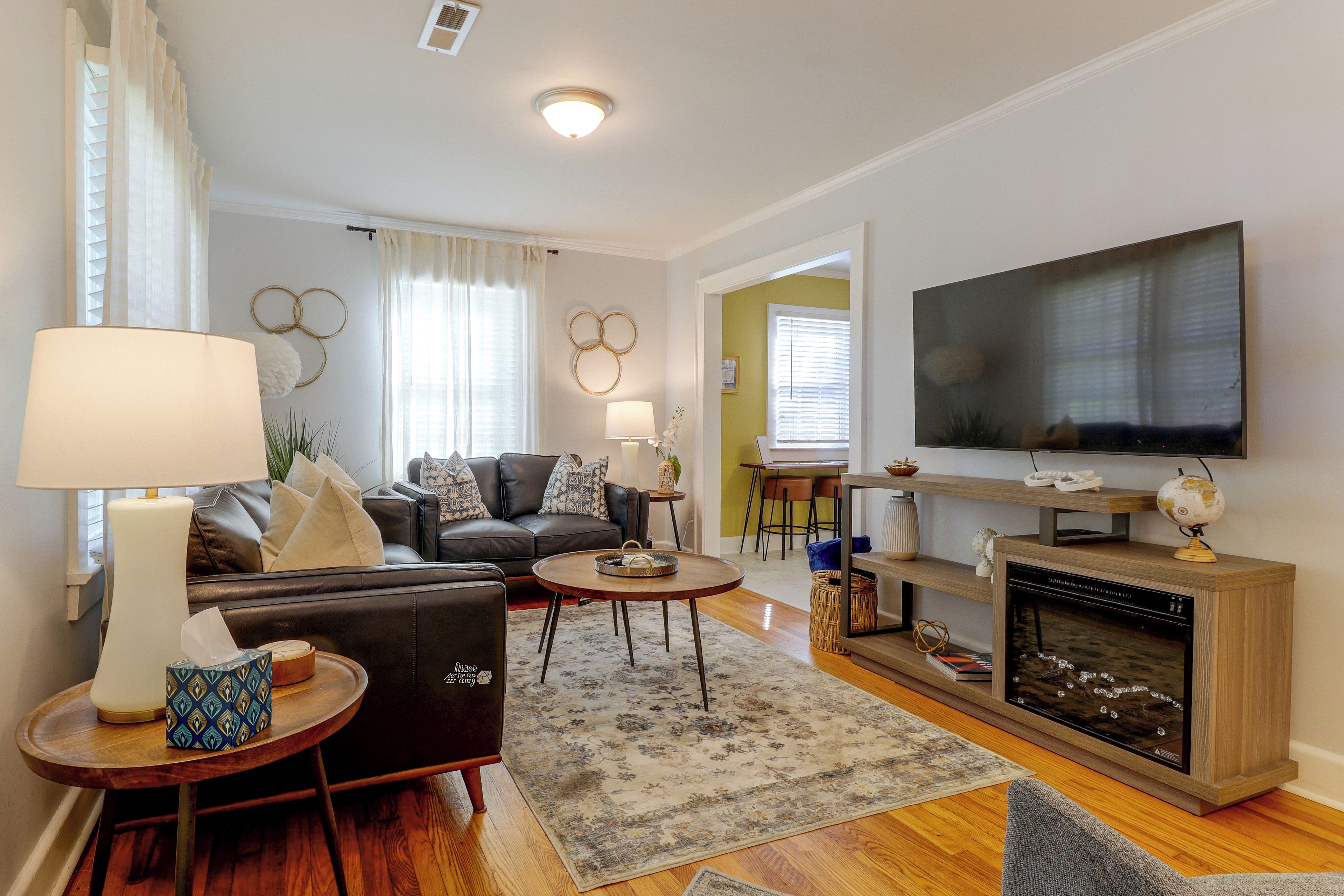 Een moderne woonkamer met een bank, salontafel, televisie, open haard en decoratieve objecten.