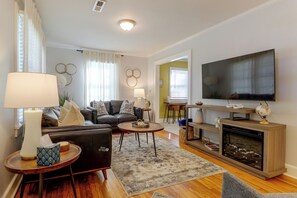 Un salon moderne comprenant un canapé, une table basse, un téléviseur, une cheminée et des objets de décoration.