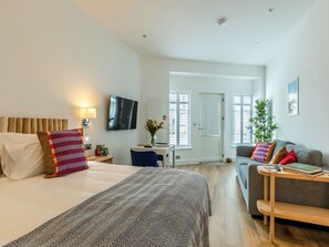 Ein modernes Hotelzimmer mit einem großen Bett, einer Couch, einem kleinen Tisch und einem Fernseher.
