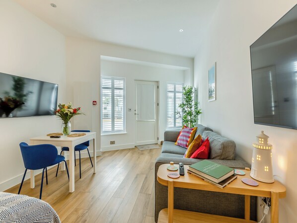 Ein modernes Wohnzimmer mit einer Couch, einem Couchtisch, einem Fernseher und einem Essbereich mit Stühlen.