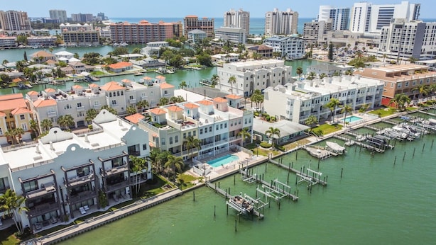 A marina with boats docked, surrounded by buildings with balconies and a pool area. - Waterfront 4-level Townhome with Rooftop Deck! (Clearwater Beach)