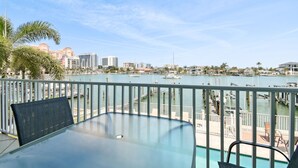 A balcony with a glass table and chairs overlooking a marina with boats and buildings in the background. - Waterfront 4-level Townhome with Rooftop Deck! (Clearwater Beach)
