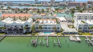 A coastal hotel with multiple buildings, a marina, and a bridge in the background. - Waterfront 4-level Townhome with Rooftop Deck! (Clearwater Beach)