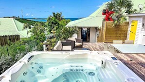 Een bubbelbad met uitzicht op de oceaan en een huis met een gele deur.