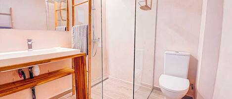 Une salle de bain moderne avec une douche à parois de verre, un meuble-lavabo en bois et des toilettes blanches.