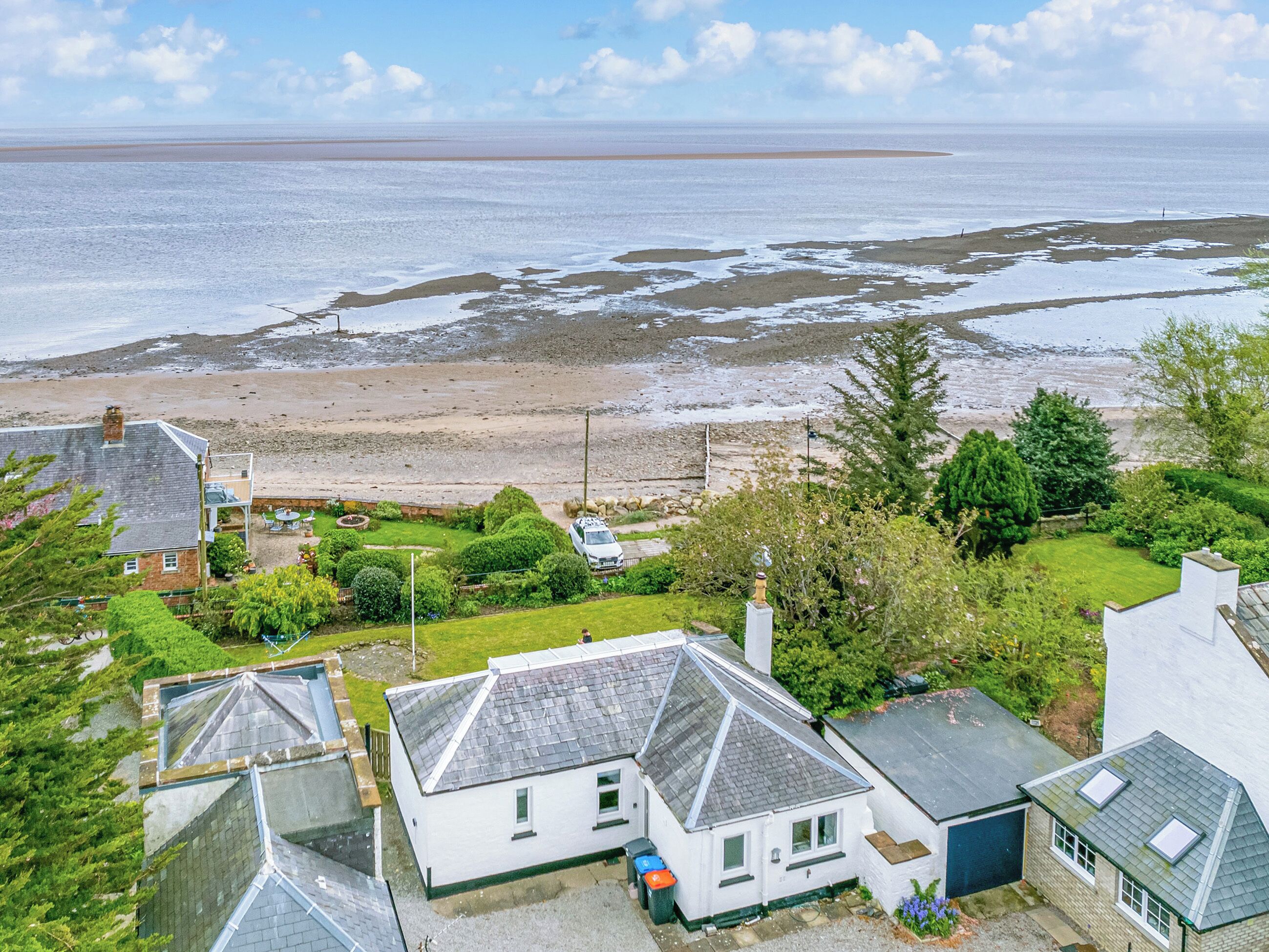 A coastal residential area with houses, a beach, and a view of the sea.