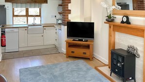 A modern kitchen with white cabinets, a built-in oven, and a wooden countertop. - Lower Axford Cottage (Callington)