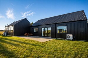 A modern building with a flat roof, large windows, and a picnic table in the foreground. - The Big House, Twizel (Twizel)