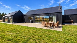 A modern building with a patio area featuring a table and chairs. - The Big House, Twizel (Twizel)