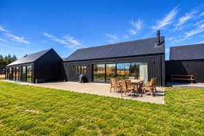 A modern building with a patio area featuring a table and chairs. - The Big House, Twizel (Twizel)