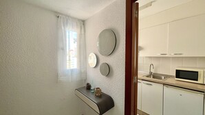 A compact kitchen with white cabinets, a built-in microwave, and a small countertop. - ALBATROS APARTMENT (R133) (Benidorm)