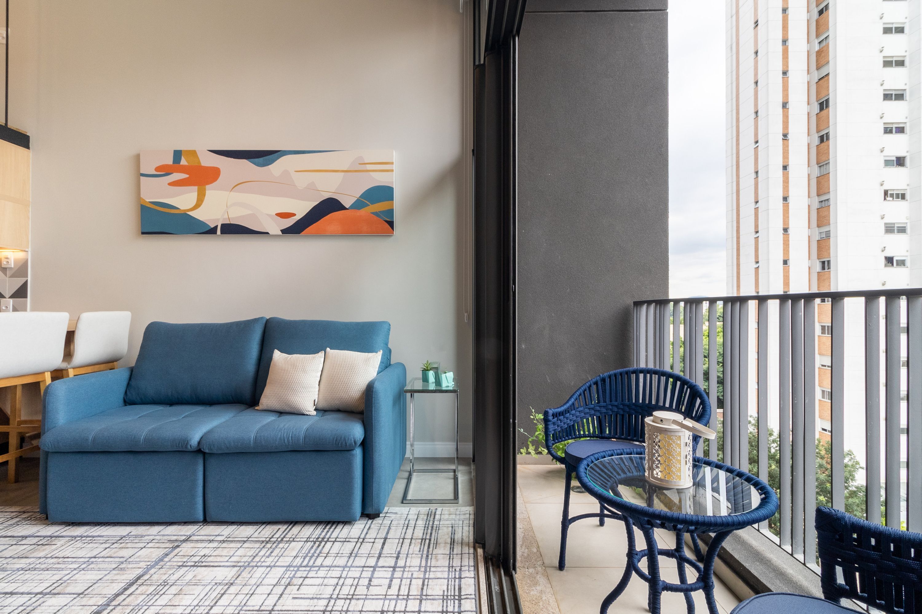 Un balcon avec un canapé bleu, une petite table et des chaises bleues.