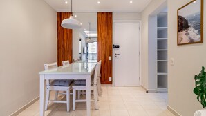 A dining area with a glass table and chairs, wooden paneling, and a white door leading to a balcony. - Ai78-902 in S o Paulo (São Paulo)