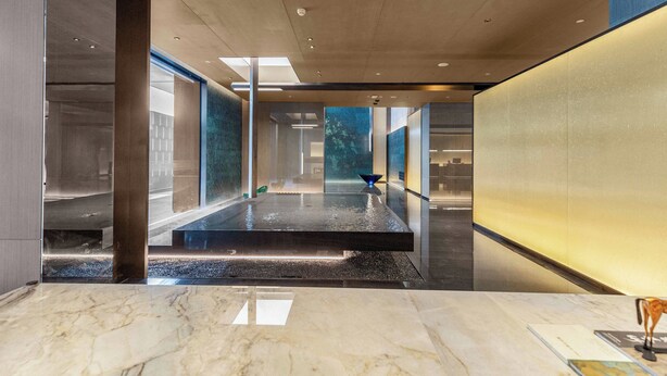 A modern hotel lobby with a central water feature, glass walls, and a marble reception desk. - Holiday Inn Express Hangzhou Jiangnan by IHG (Hangzhou)