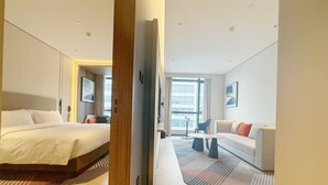 A modern hotel room with a large bed, a sofa, and a dining table. There is a view of the city through the windows. - Holiday Inn Express Hangzhou Jiangnan by IHG (Hangzhou)