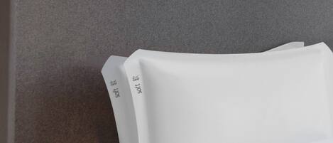 A bed with white linens and a headboard with a textured surface.