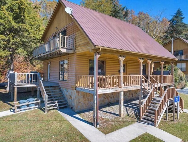 A log cabin with a porch, a staircase, and a satellite dish. - Beautiful 6 Bedroom Cabin with Hot Tub and a Lakeview of Dale Hollow Lake #12 (Byrdstown)