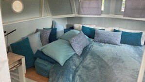 Ein gemütliches Schlafzimmer mit Bett, Kissen und einem Fenster mit Vorhängen.