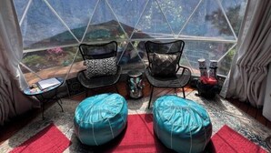 Ein Zimmer in Form einer Geodätischen Kuppel mit zwei Sesseln, einem kleinen Tisch und einem roten Teppich.