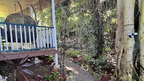 Un espacio de estar techado al aire libre con un banco de madera y barandilla de metal.