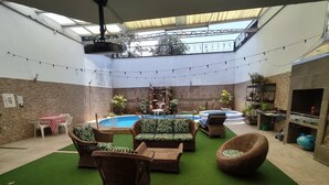An indoor patio with a pool, wicker furniture, and a barbecue area. - Charming House, Convenient Location in Bucaramanga (Bucaramanga)