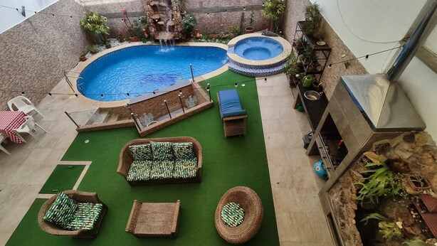 A rooftop pool area with two hot tubs, a waterfall feature, and multiple seating options including a sofa and chairs. - Charming House, Convenient Location in Bucaramanga (Bucaramanga)