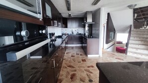 A modern kitchen with dark wood cabinets, stainless steel appliances, and a stone-patterned floor. - Charming House, Convenient Location in Bucaramanga (Bucaramanga)