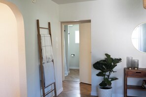 Ein Flur mit einer Holzleiter, die an der Wand lehnt, einer Topfpflanze und einem Spiegel auf einem Holztischchen.