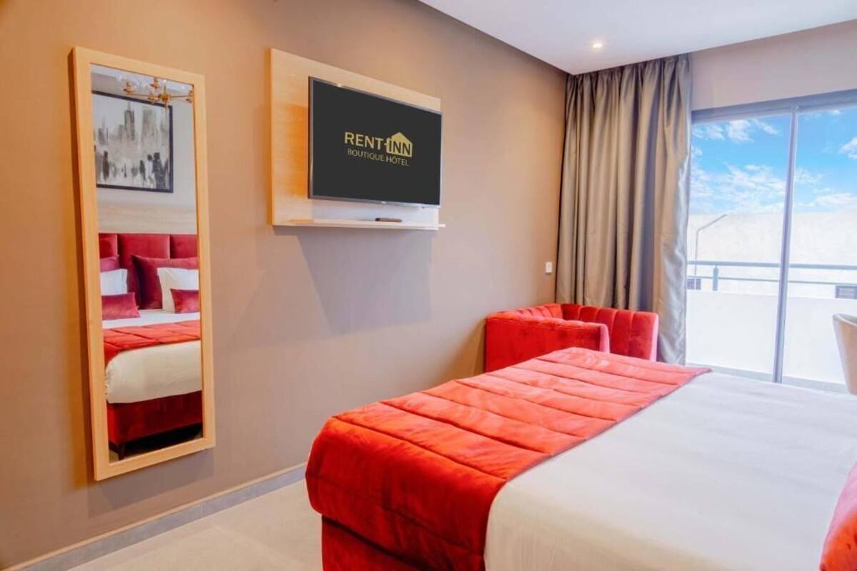 A hotel room with a bed, a TV, and a large window.