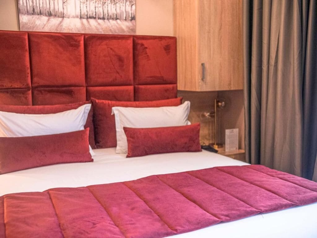 A bed with a red headboard, white pillows, and a red blanket.