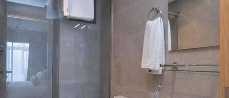 Un baño moderno con cabina de ducha de vidrio, inodoro, lavamanos con espejo y barra para toallas.