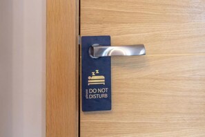 Una puerta con un cartel que dice 'NO MOLESTAR' y un símbolo de cama.