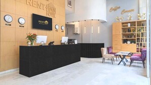 Un espace d’accueil moderne avec un comptoir noir, des horloges et un coin café.