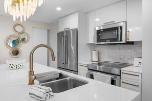 A modern kitchen with stainless steel appliances, a white countertop, and a gold faucet. - Oceanview Penthouse · Pool · Sleeps 6 (San Juan)