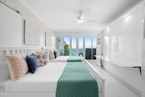A modern hotel room with a bed, a desk, and a view of the ocean. - Oceanview Penthouse · Pool · Sleeps 6 (San Juan)