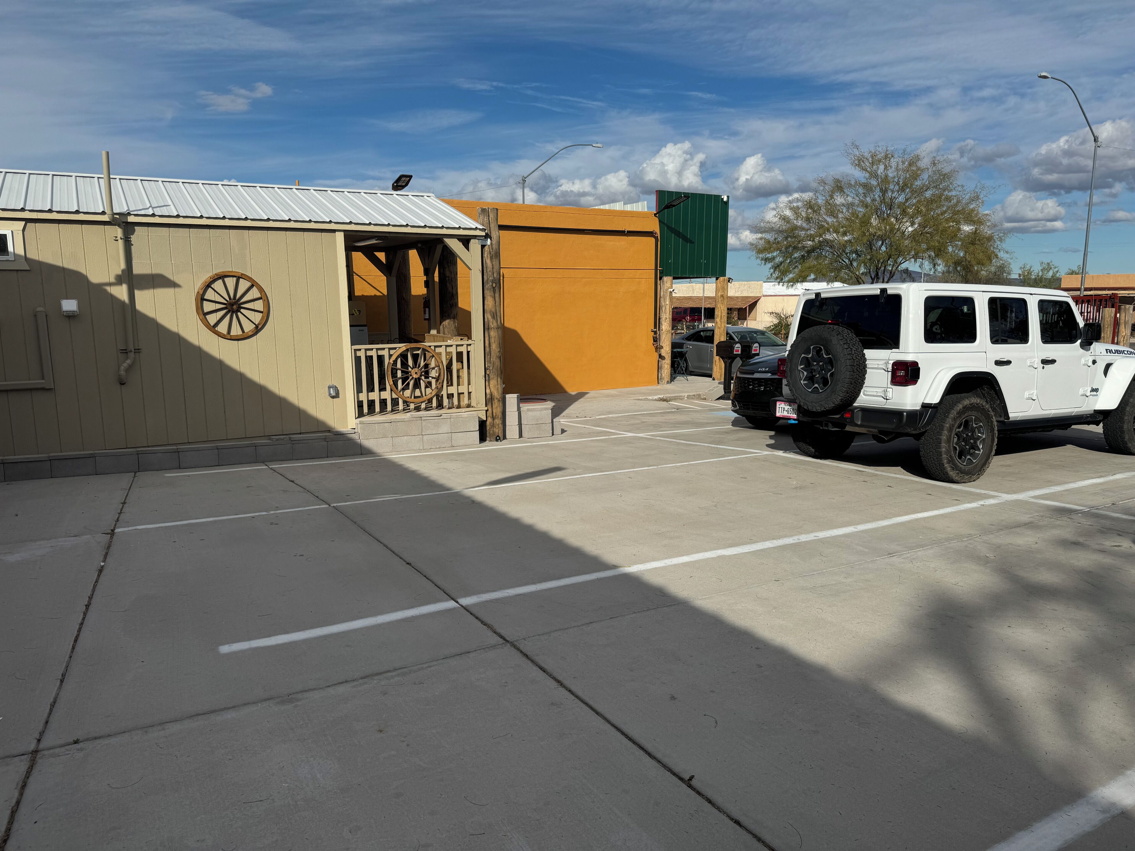 A parking lot with a white Jeep and a building with a green sign.